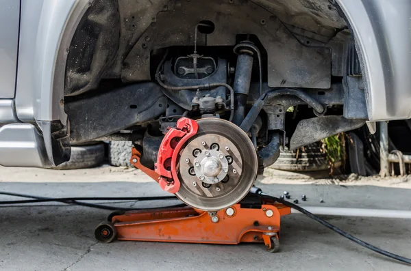 Freio de disco dianteiro no carro em processo de substituição de pneus novos. O — Fotografia de Stock