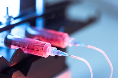 Kırmızı sıvı ortamı şırıngalardan ve esnek tüplerden bilimsel bir laboratuvar deneyinde kullanmak üzere küçük bir çip oluşturun..