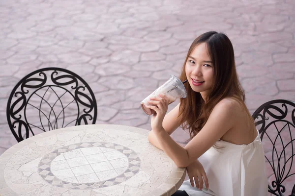 Hermosa chica asiática en vestido blanco sentado en una silla y beber —  Fotos de Stock