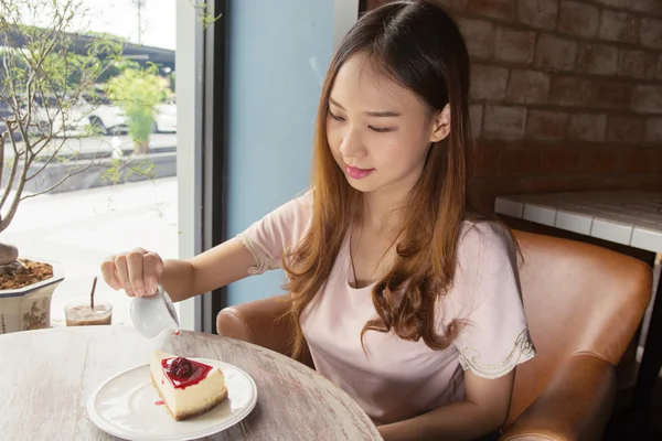 Hermosa mujer asiática vertiendo salsa de arándanos cubierta de pastel de queso — Foto de Stock