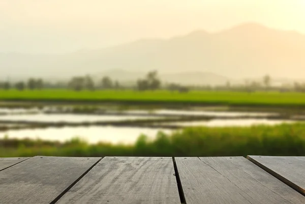 Imagem desfocada e desfocada de madeira de terraço e belo arroz paddy ao pôr do sol para uso em segundo plano — Fotografia de Stock