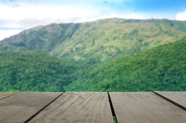 Imagem desfocada e desfocada de madeira de terraço e bela montanha verde para uso de fundo — Fotografia de Stock