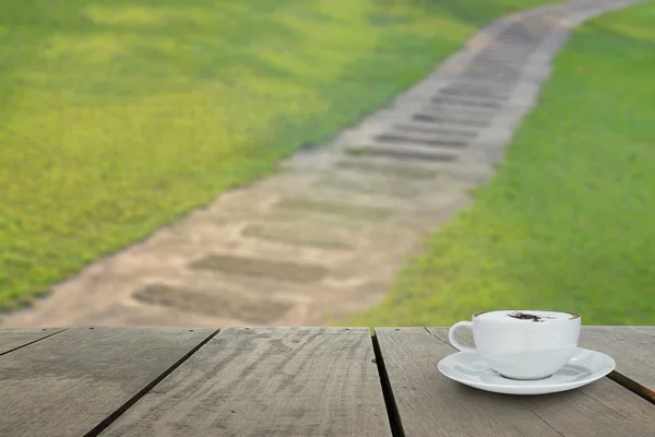Terras hout en cappuccino koffie op gras met voetpad — Stockfoto