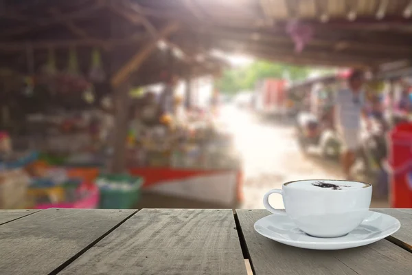 Koffiekopje op terras hout en lokale markt achtergrond wazig — Stockfoto