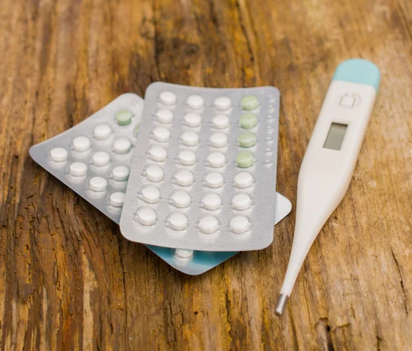 Birth control pills and thermometer — Stock Photo, Image