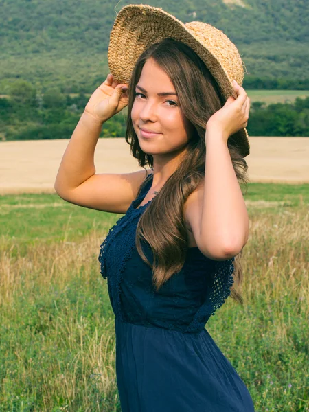 Retrato de una hermosa joven con flores en el campo — Foto de Stock