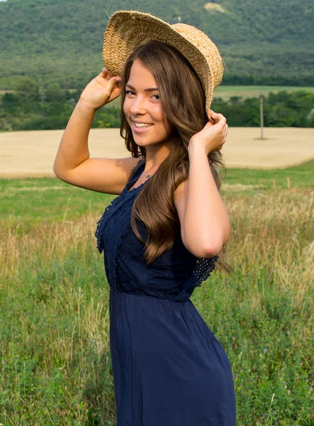 Retrato de una hermosa joven con flores en el campo — Foto de Stock