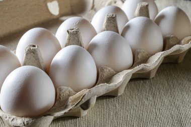 Karton kasette beyaz tavuk yumurtası. Kumaş arka plan. Kapat..