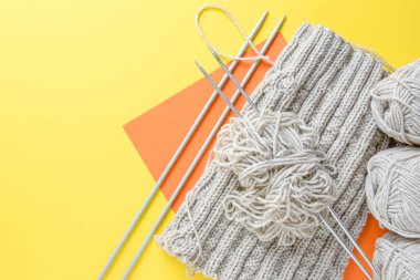 Düz örgü örüyorum. Yatay örgü kolajı, parlak bir arka planda iplik ve örgü iğneleri. Boşluğu kopyala.