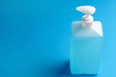  Antiseptik şişe, pompa ile donatılmış, mavi arka planda. Sağlık hizmetleri kavramı. Boşluğu kopyala.