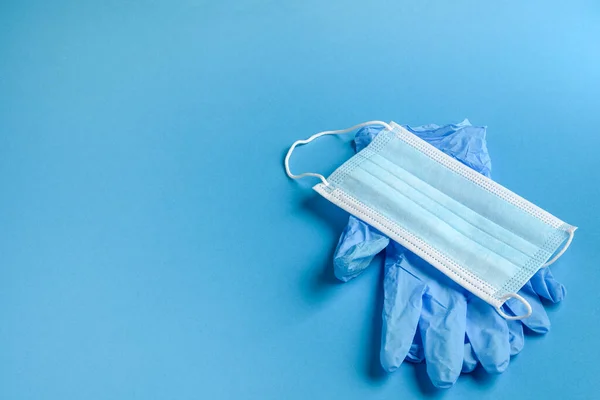 A medical mask and medical gloves on a blue background. The concept of healthcare. Copy space.