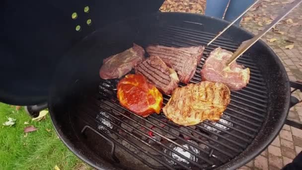 Człowiek gotowanie steków na grillu — Wideo stockowe