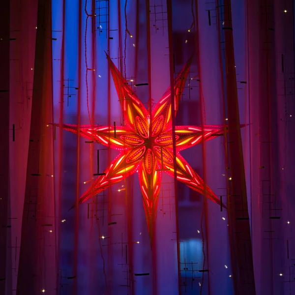 Noel tatili boyunca bir kış akşamında pencerede dekoratif bir Noel yıldızı