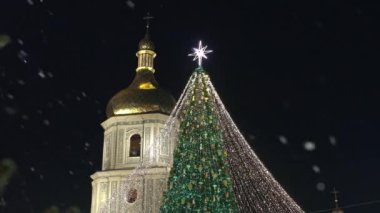 Yılbaşı gecesi Kiev 'deki Aziz Sophia Katedrali' nin arka planındaki Noel ağacı. Katedral binası aydınlandı ve Noel ağacı çelenklerle süslendi..