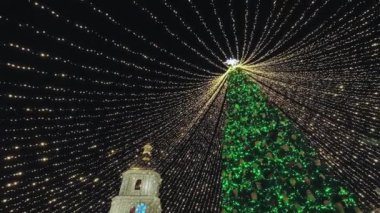 Parlayan çelenkleri ve parıldayan ışıkları olan Noel ağacı. Noel ağacının tepesinde bir Noel yıldızı var..