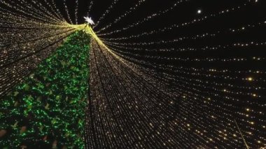 Parlayan çelenkleri ve parıldayan ışıkları olan Noel ağacı. Noel ağacının tepesinde bir Noel yıldızı var..