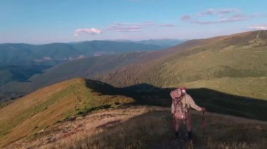 Sırt çantası ve yürüyüş direkleri olan bir turist dar bir yoldan gider..