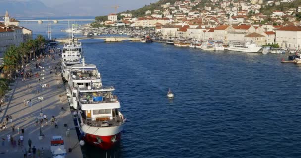 人々は海岸に係留豪華なヨットに近いクロアチアのトロギルの古い部分のウォーターフロントに沿って散歩します — ストック動画
