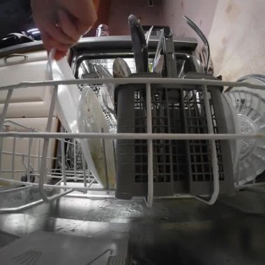 Kirli bulaşıkları çamaşır makinesine yükleyen kişi döngü başlamadan önce