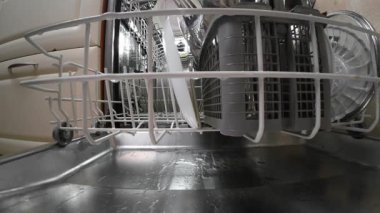 Elleri bulaşık makinesine koyuyor ve modern ev mutfağında düzenli temizlik için kaydırak asıyor.