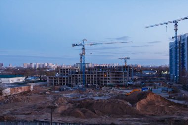Construction site with cranes and unfinished buildings at dusk, city skyline, urban development, business, industry, real estate, landscape, spring evening