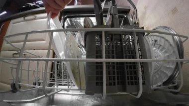 Tabakları bulaşık sepetine koyuyor ve modern mutfakta düzenli temizlik ve hijyen için içeri sokuyor.