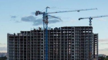 Vinçlerin gökyüzünde hareket eden bulutlarla apartman kompleksi inşa etme zamanı, inşaat, kentsel gelişim, takım çalışması, şehir ve mühendisliği gösteriyor