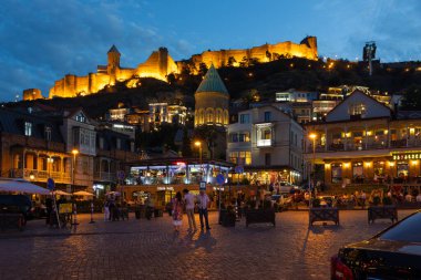 Tiflis, Georgia- 30 Eylül 2018: Aydınlatılmış Narikala Kalesi hareketli bir Tiflis şehir meydanına bakıyor..