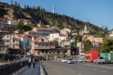 Tiflis, Georgia- 05 Ekim 2018 Tiflis, Gürcistan 'ın canlı şehir manzarası, geleneksel binalar, yol trafiği ve ikonik dağ heykeli. Güneşli bir günde şehir seyahatini ve tarihi mimariyi yakalar.