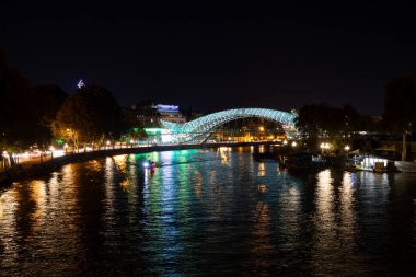 Tiflis, Georgia- 30 Eylül 2018: Modern Barış Köprüsü, Gürcistan 'ın Tiflis kentindeki karanlık Mtkvari Nehri üzerindeki canlı renklerini yansıtan binlerce LED ışığıyla çarpıcı bir şekilde aydınlatılmıştır..