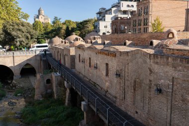 Tiflis, Georgia- 3 Ekim 2018: Gürcistan 'ın Tiflis kentindeki tarihi Abanotubani bölgesinin manzarası, içinde kubbeleri olan ünlü tuğla kükürt hamamlarının ve nehir akarsularının üzerinden geçişi yer alıyor..