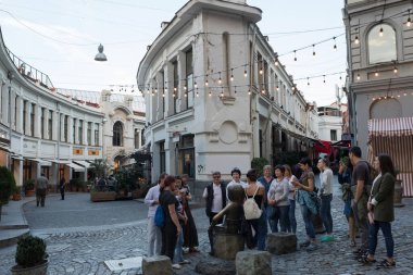 Tiflis, Georgia-- Ekim 04, 2018: Eski Tiflis 'te bir kaldırım taşı caddesini gezen bir grup turist. Tarihi kent manzarasında geleneksel mimari ve sicim ışıkları yer almaktadır.