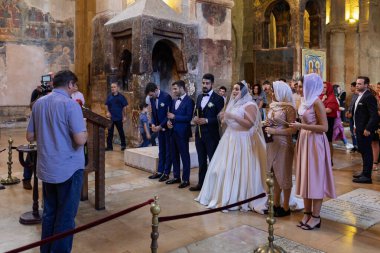 Mtskheta, Georgia-- 03 Ekim 2018: Gelin ve damat, Mtskheta, Gürcistan 'daki tarihi Svetitskhoveli Katedrali' nde düzenlenen geleneksel Ortodoks düğün töreninde ellerinde mumlar tutuyorlar.