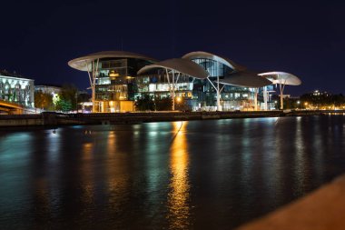 Tiflis, Georgia- Ekim 04, 2018: Mantar şekilli eşsiz çatısı ile modern Kamu Hizmet Salonu 'nun gece görüşü, Tiflis, Gürcistan' daki Mtkvari Nehri 'nde aydınlanıyor ve yansıtılıyor..