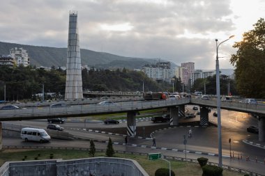Tiflis, Georgia- 01 Ekim 2018: Tiflis, Gürcistan 'da yoğun, çok katlı bir otoyol kavşağı, yoğun araba trafiği ve tepe ve şehir binalarının arka planında görülebilen modern uzun bir anıt.
