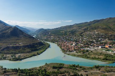 Mtskheta, Gürcistan 'da Aragvi ve Kura nehirlerinin kesişiminin manzarası. Tarihi kasabada mavi gökyüzünün altında Svetitskhoveli Katedrali yer almaktadır..