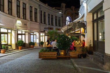 Tiflis, Georgia- Ekim 04, 2018: Eski Tiflis, Gürcistan 'da kaldırımlı yaya caddesinde, sıcak sokak ışıkları altında yemek yiyen insanların bulunduğu rahat bir açık hava restoran terası..