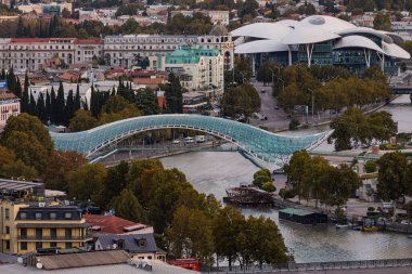 Tiflis 'teki Barış Köprüsü ve Kamu Hizmetleri Salonu' nun manzarası. Modern mimari, Gürcistan 'ın başkenti Kura Nehri boyunca yer almaktadır.