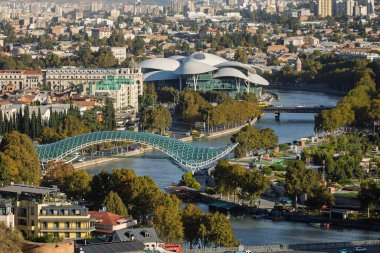 Tiflis 'teki modern Barış ve Kamu Hizmetleri Köprüsü manzarası. Günümüz mimarisi güneşli bir günde Kura Nehri 'nin kıyısında duruyor..