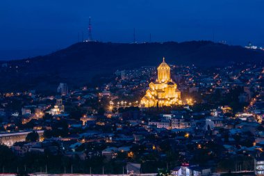 Tiflis 'in Kutsal Üçlü Katedrali' nin (Sameba) güzel manzarası, gün batımından bir saat sonra şehrin ufuk çizgisine çarpıcı bir şekilde aydınlandı..