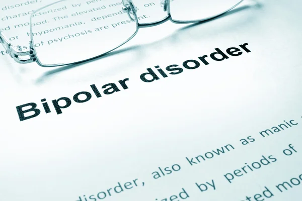 Διπολική διαταραχή σημάδι σε ένα χαρτί και γυαλιά. — Φωτογραφία Αρχείου