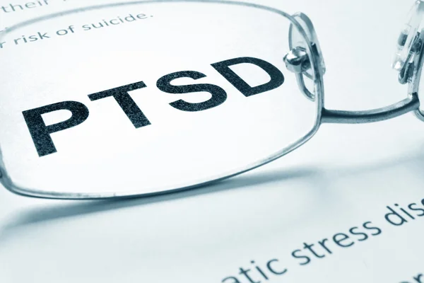 PTSD tecken på ett papper och glas. — Stockfoto