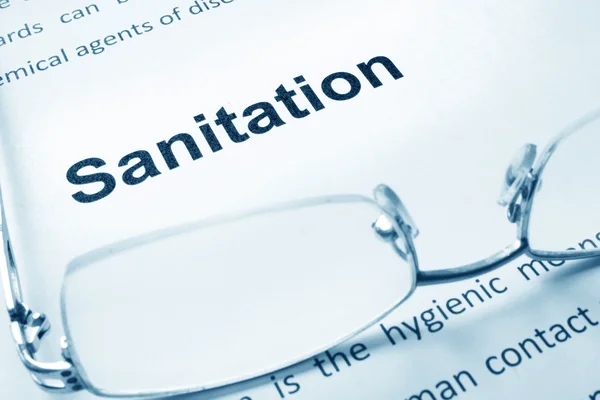 Sanitasyon işareti bir kağıt ve gözlük. — Stok fotoğraf