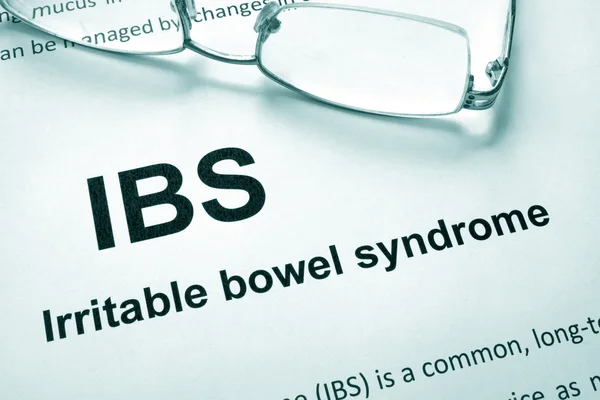 Kertas dengan kata sindrom irritable bowel syndrome (IBS) dan kacamata . — Stok Foto