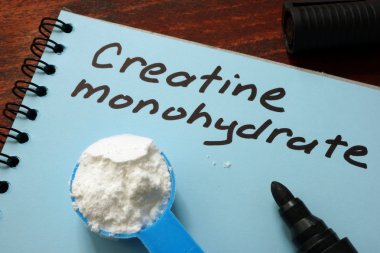 Notebook with  sign Creatine monohydrate and scoop with white powder. clipart