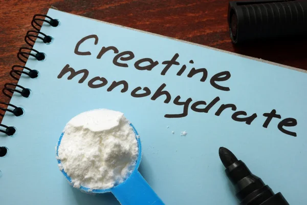 Notebook s znamení Kreatin monohydrát a lopatka s bílým práškem. — Stock fotografie