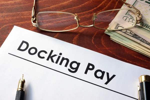 Papír s slov Docking zaměstnanec platit na stůl. — Stock fotografie