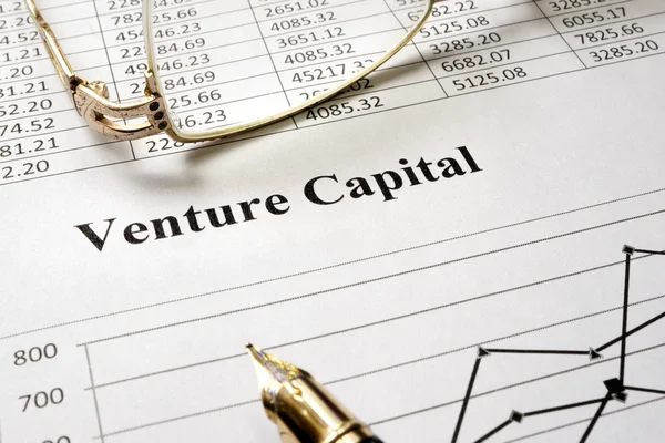 Teken risicodragend kapitaal op een papier en glazen. — Stockfoto