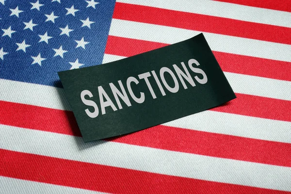 Stati Uniti bandiera e sanzioni parola sul pezzo di carta nero. — Foto Stock