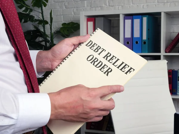 Homem lê sobre ordem de alívio da dívida DRO no livro. — Fotografia de Stock